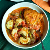 chicken cacciatore served in a white bowl a one pan meal with chicken potatoes green beans and fresh tomatoes