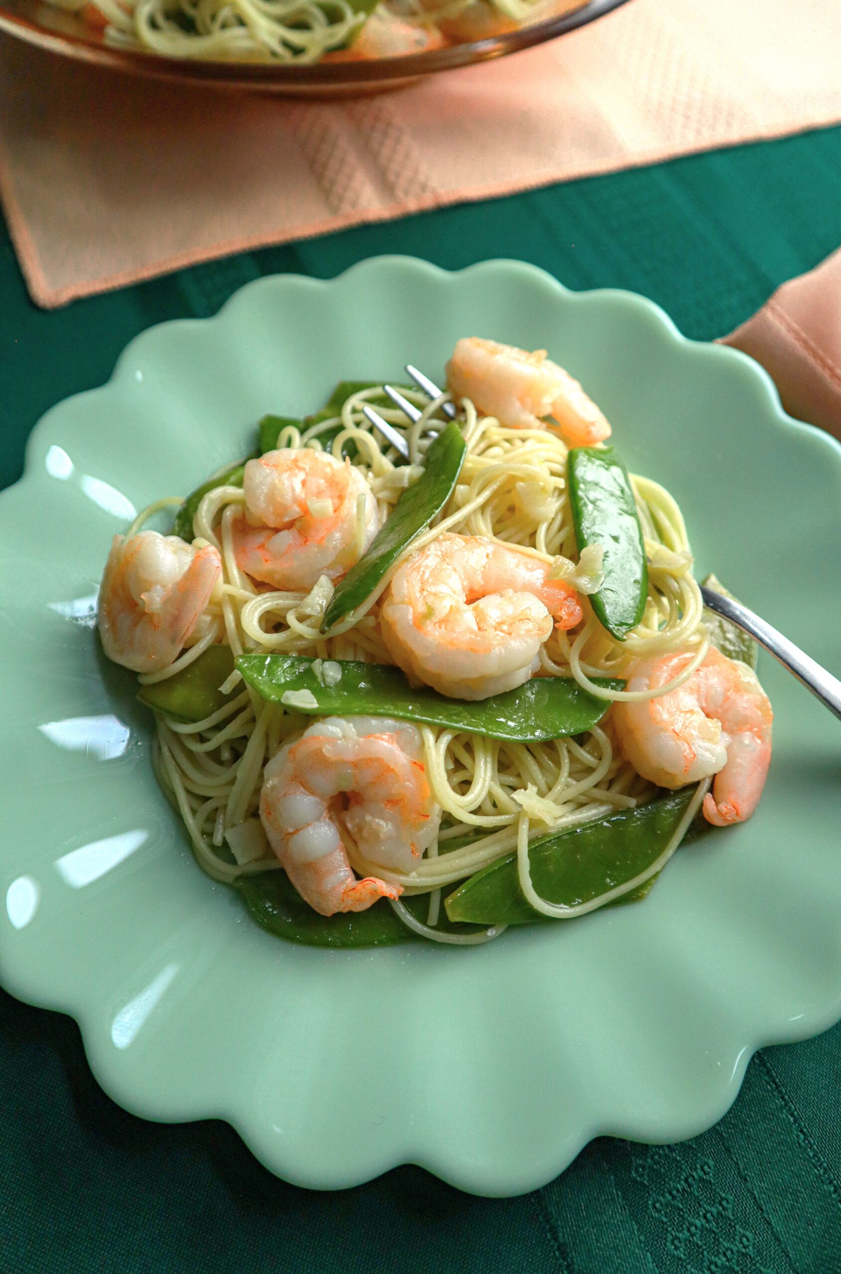 shrimp with pea pods with angel hair pasta single serving on green plate