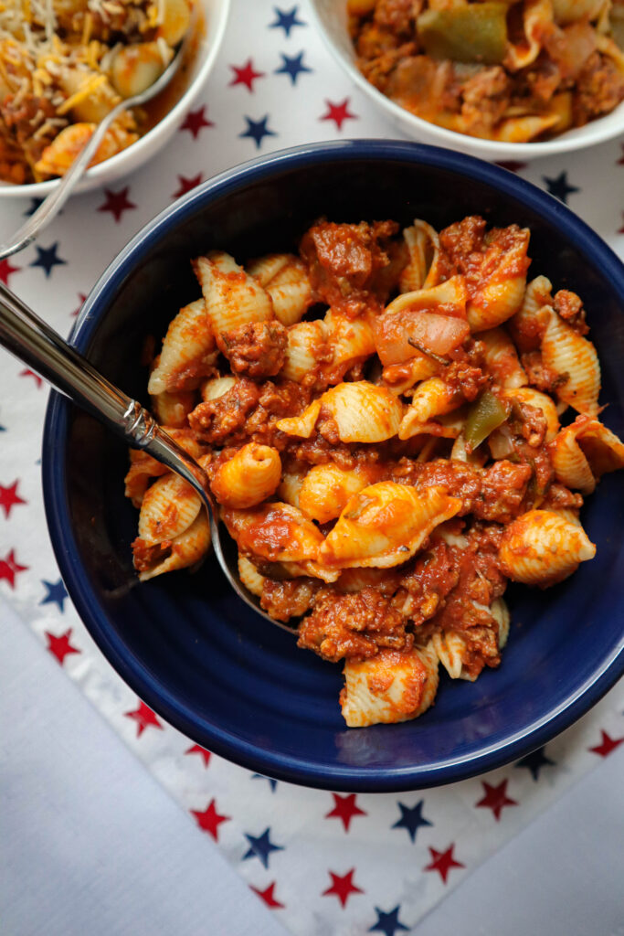 american chop suey with pasta shells served from blue bowl red white and blue stars cloth under bowl