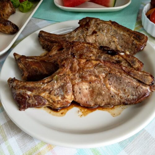 country style ribs marinated and served on a platter watermelon and grape tomatoes on table