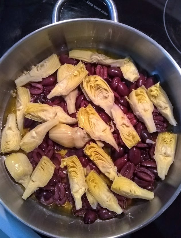 olives and artichoke hearts in skillet with olive oil and garlic