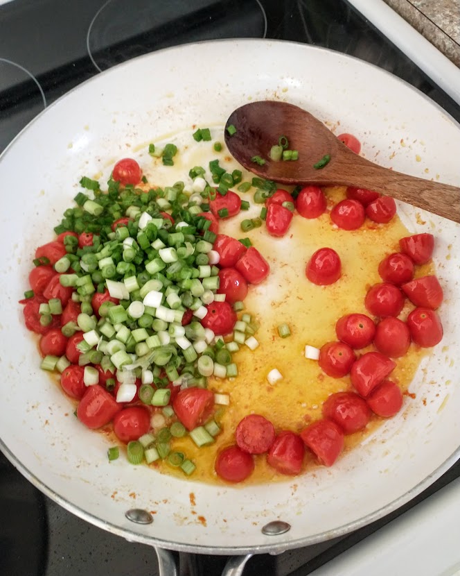 kids meal green onion added to the tomatoes in skillet