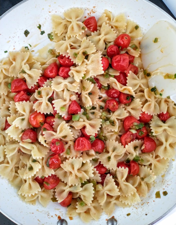 kids meal bowtie pasta added to cooked grape tomatoes and green onion