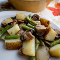potato mushroom and green ben saute served on a plate as a side dish