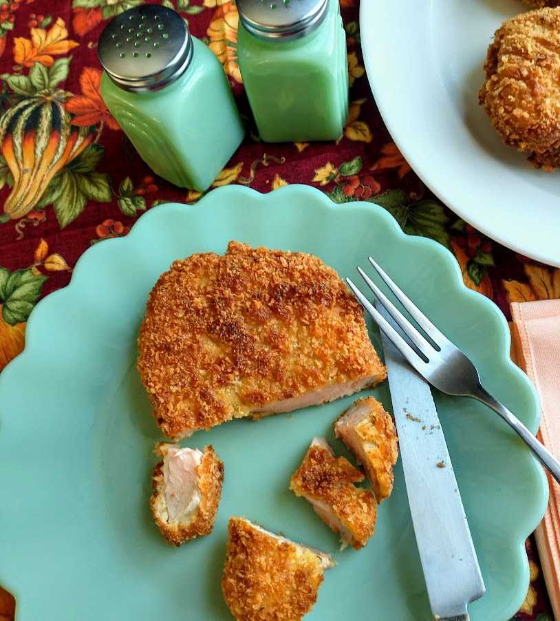 panko crusted pork loin cutlets served and cut up on a green dish with knife and fork