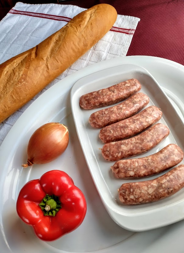 ingredients for sausage sub sandwiches italian sausage red pepper yellow onion and french bread