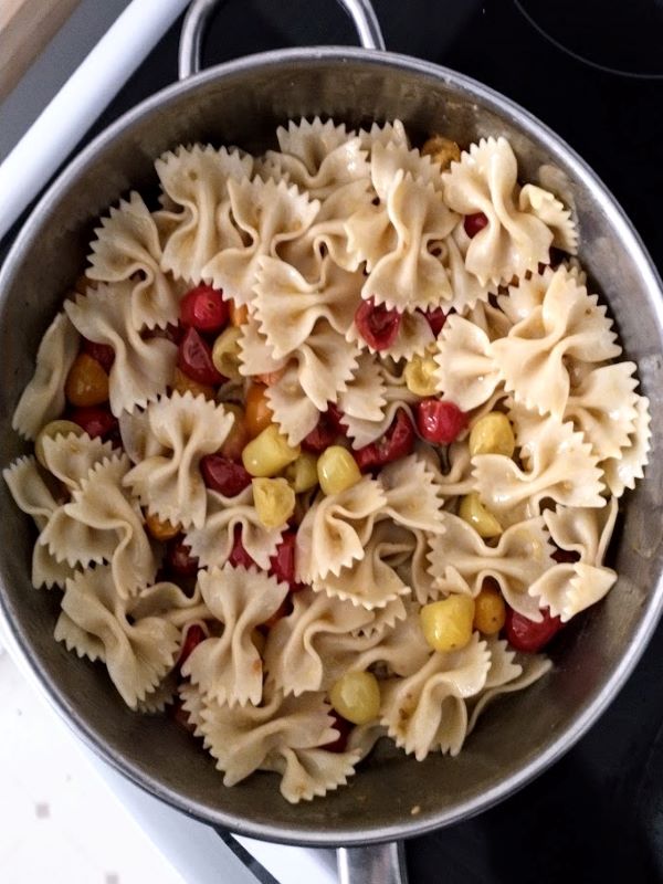 bowtie farfalle  pasta added to skillet with multi colored grape tomatoes olive oil and butter