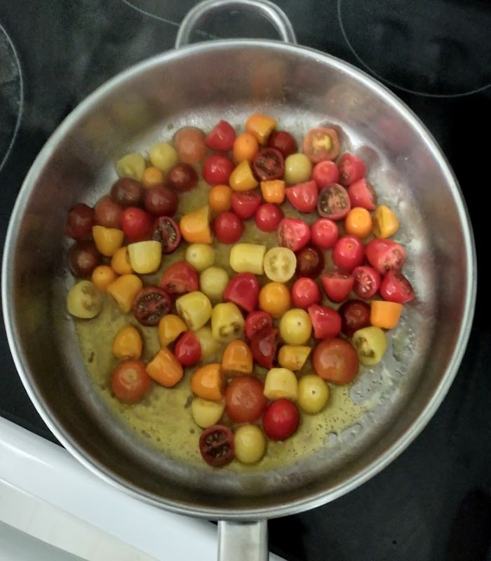 skillet with multi colored grape tomatoes in olive oil