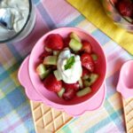 kids salad with strawberries and cucumber with a dollop of sour cream and honey topping served in kids dish