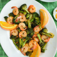 shrimp with broccoli in a homemade orange sauce served on a platter with orange wedges
