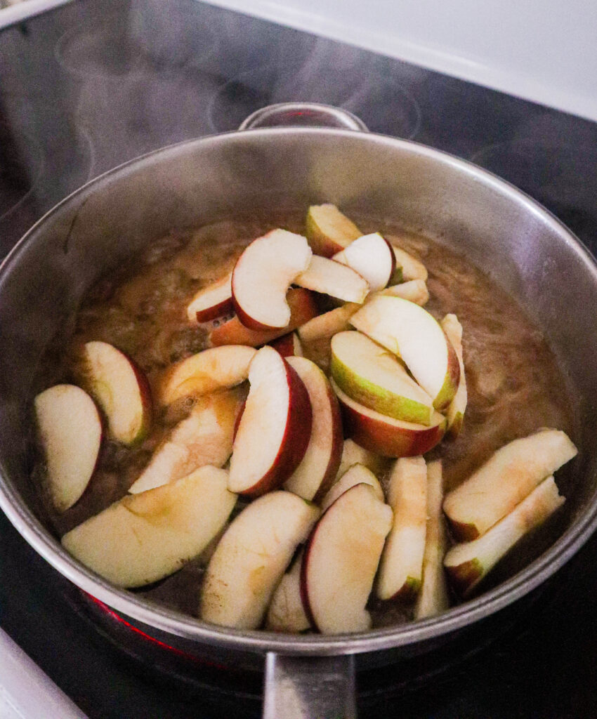 sliced apples and cider sauce added to skillet with sauteed onions