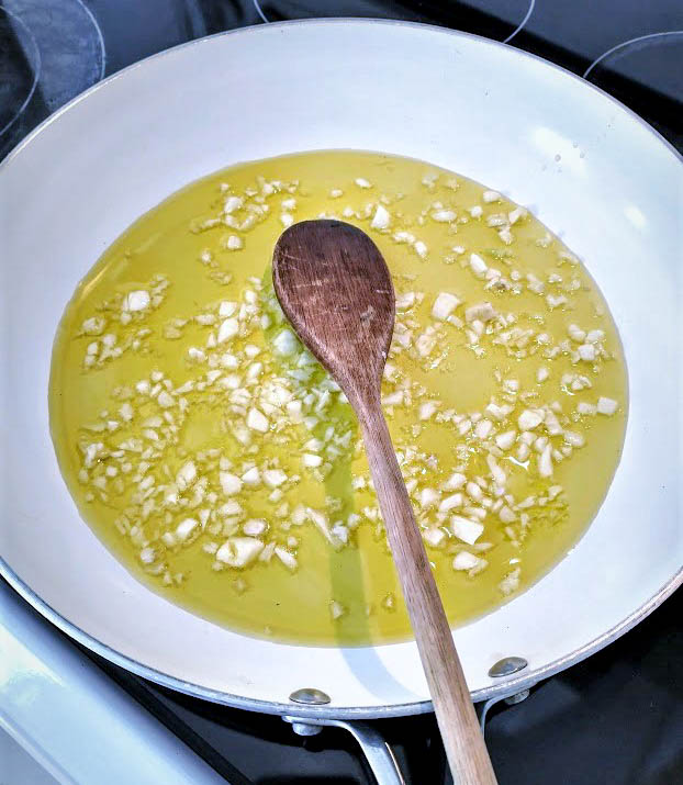 skillet on stove with olive oil and garlic