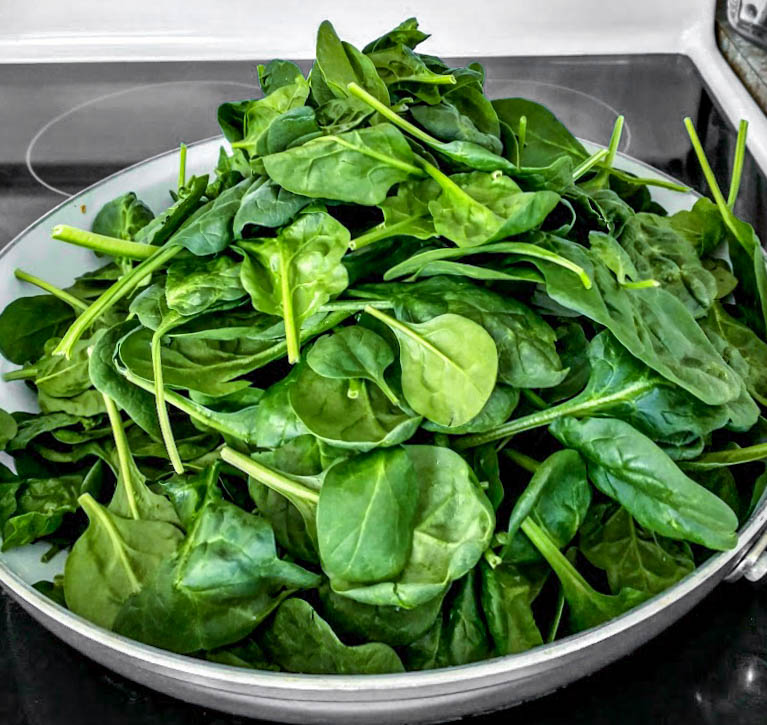 a mound of fresh spinach leaves in skillet