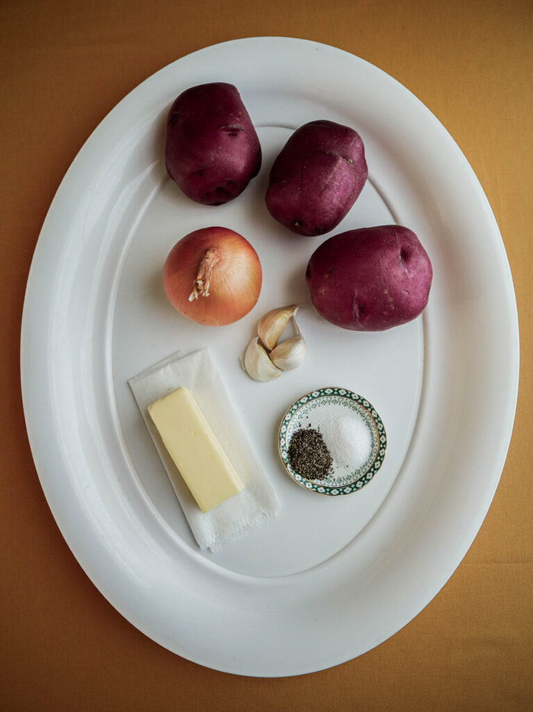 Ingredients for potato and onion in a garlic butter sauce 3 red potatoes yellow onion garlic butter salt pepper