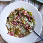cabbage and beans soup with ham served in white single serving bowl