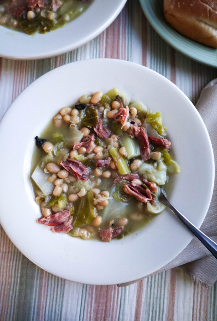 cabbage and beans soup with ham served in white single serving bowl