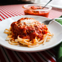 marinara sauce over pasta in white serving dish with grated cheese on top