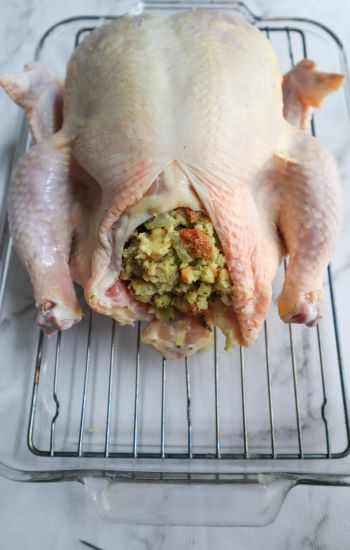 stuffing in cavity of whole chicken on roasting rack