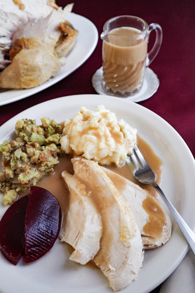 sliced chicken and gravy served with stuffing mashed potatoes and cranberry sauce