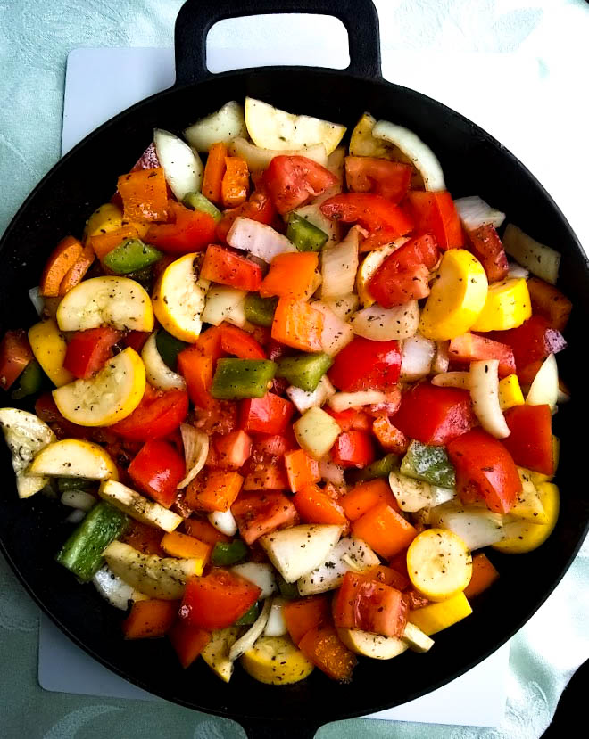 chopped vegetables covered in balsamic dressing in a cast iron skillet ready to go in the oven