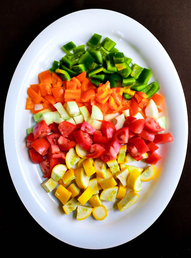 chopped green and orange sweet peppers onion roma tomatoes and yellow summer squash