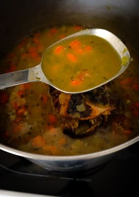 split pea soup is done shown on a large spoon over the pot of soup