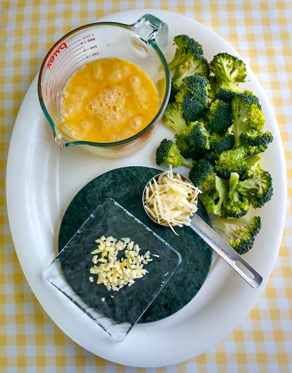 eggs mixed in measuring cup chopped broccoli grated cheddar cheese and minced garlic