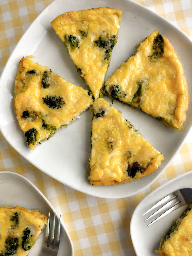 broccoli frittata cut into wedges on a serving dish at the table