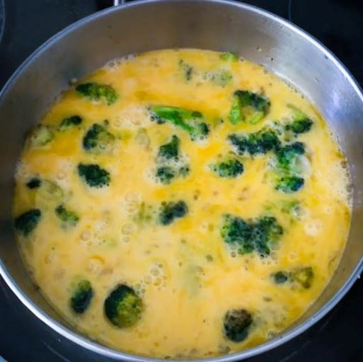 beaten eggs added to cooked broccoli in skillet