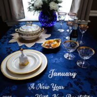 january table setting in royal blue and white with gold trimmed dishware and stemware