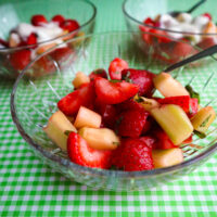 strawberry salad served in clear dessert bowl on a lime green and white tablecloth