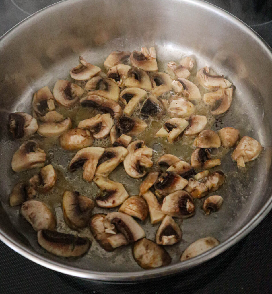 sliced mushrooms and butter sauteeing in the skillet