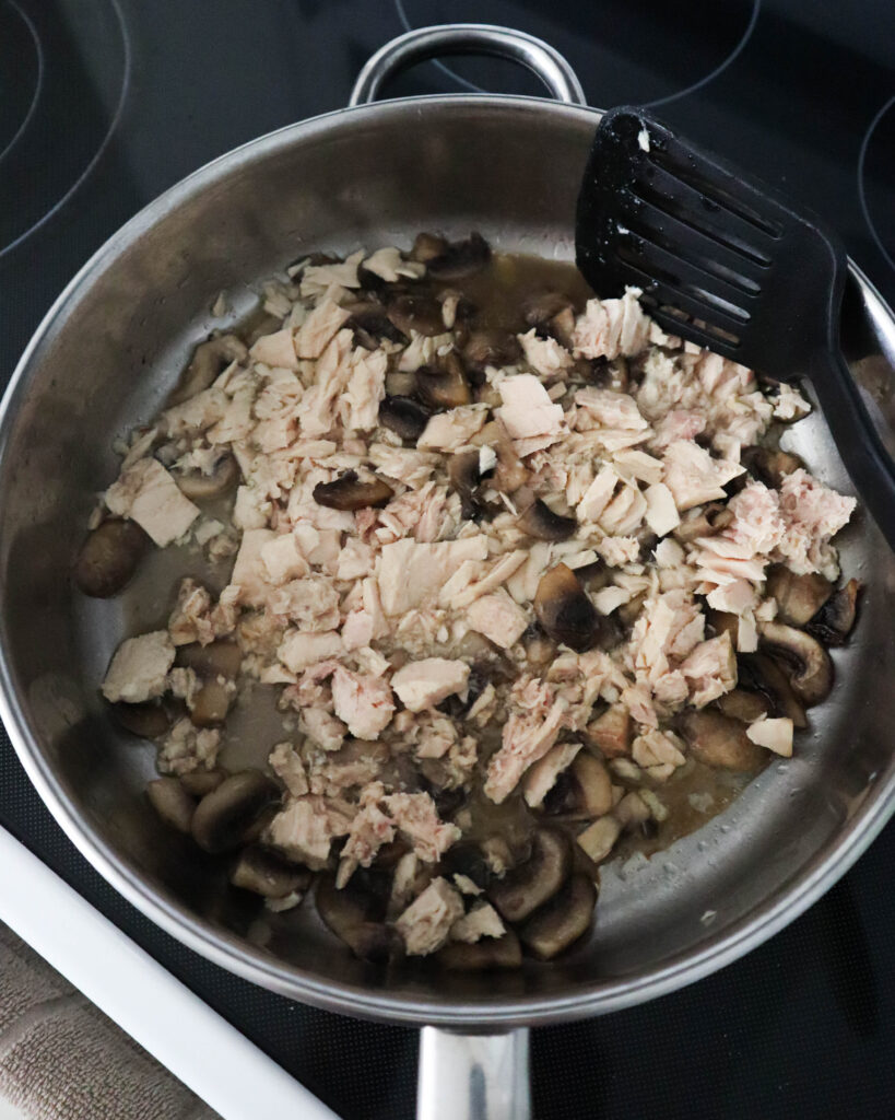 adding tuna to the mushrooms in the skillet