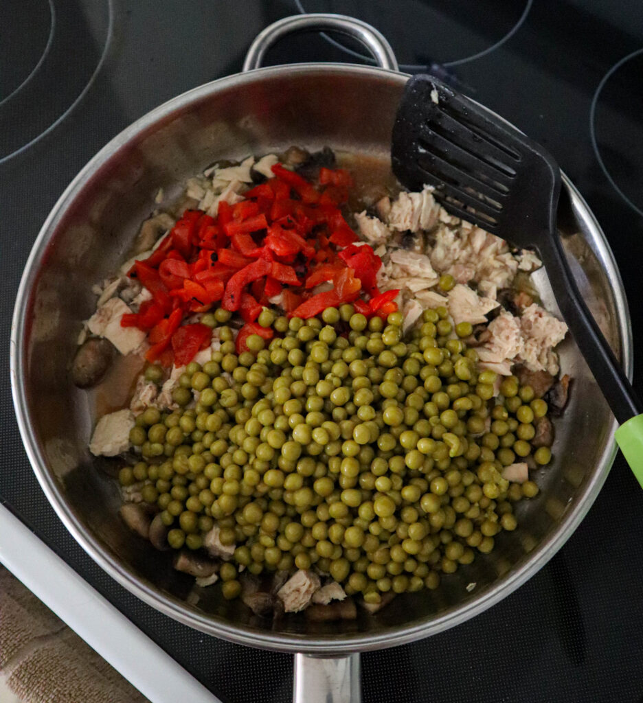 adding peas and roasted red peppers to the slillet