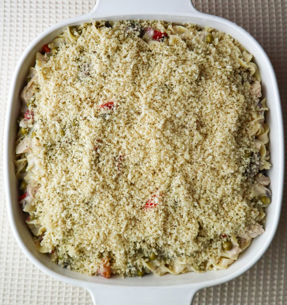 a casserole dish with tuna noodle casserole topped with buttered panko crumbs