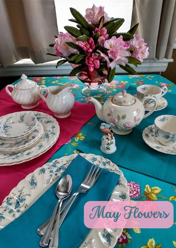 dinner table setup in teal and pink lots of flowers on dishes tablecloth and in a vase