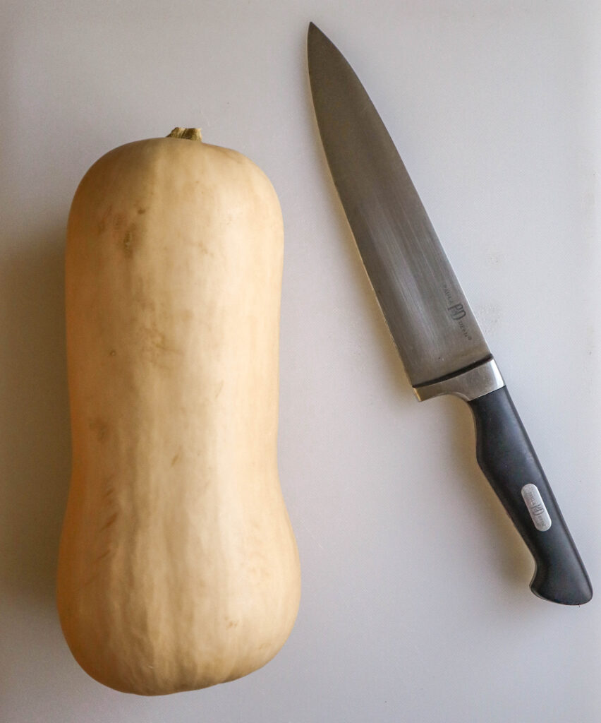 a butternut squash unpeeled and a large cutting knife
