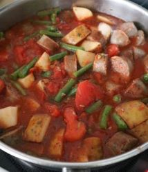 ingredients mixed in skillet tomato potato sausage green beans garlic and spices