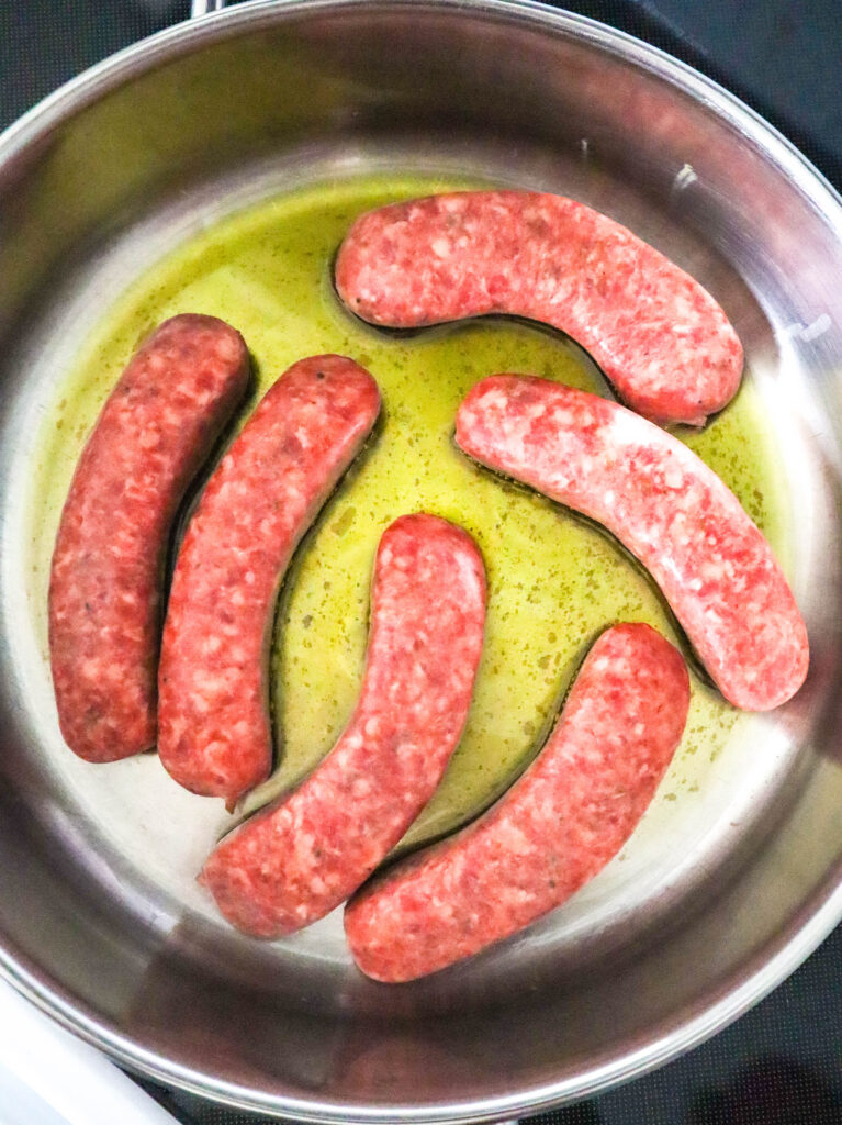 italian sausages cooking in oil in skillet
