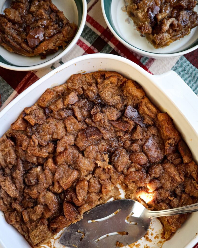 bread pudding with brown sugar topping served in baking dish with 2 servings in background