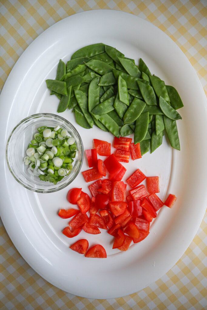 chopped scallion and red pepper trimmed snow pea pods