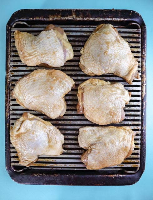 6 chicken thighs uncooked on a baking rack