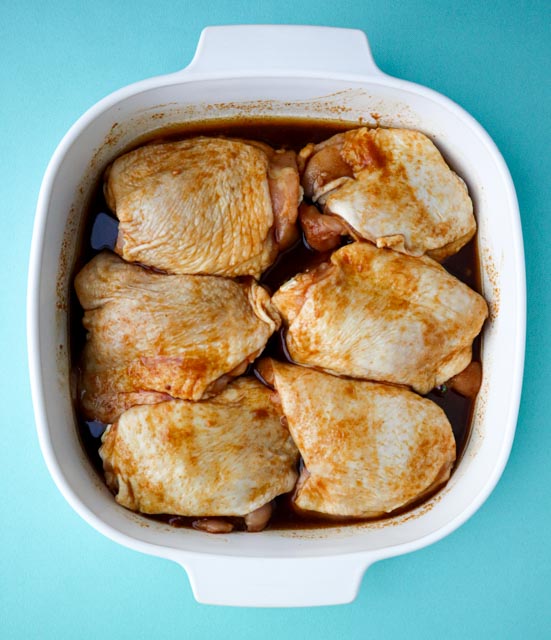 6 chicken thighs marinating in a glass baking dish